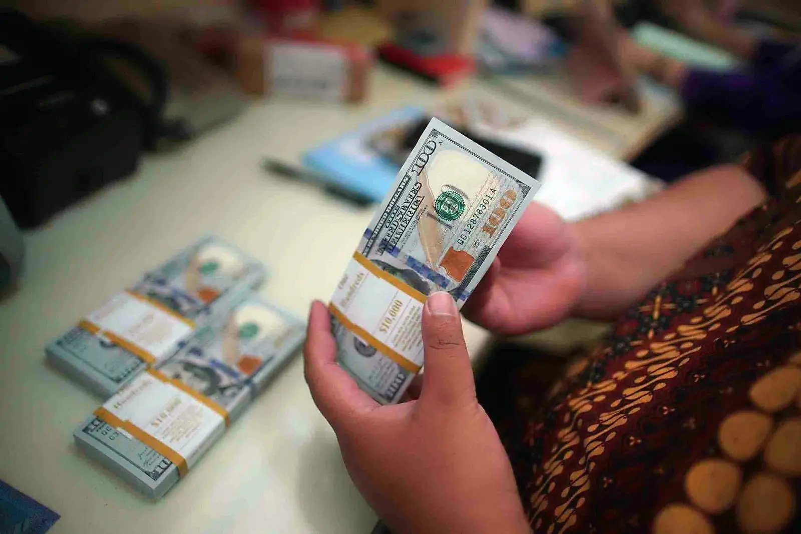 Pegawai menghitung uang dolar Amerika Serikat (USD) saat melayani pengunjung yang menukarkan valas ke rupiah di La Tunrung Money Changer, Juanda. (Foto: KabarBursa/Abbas Sandji)